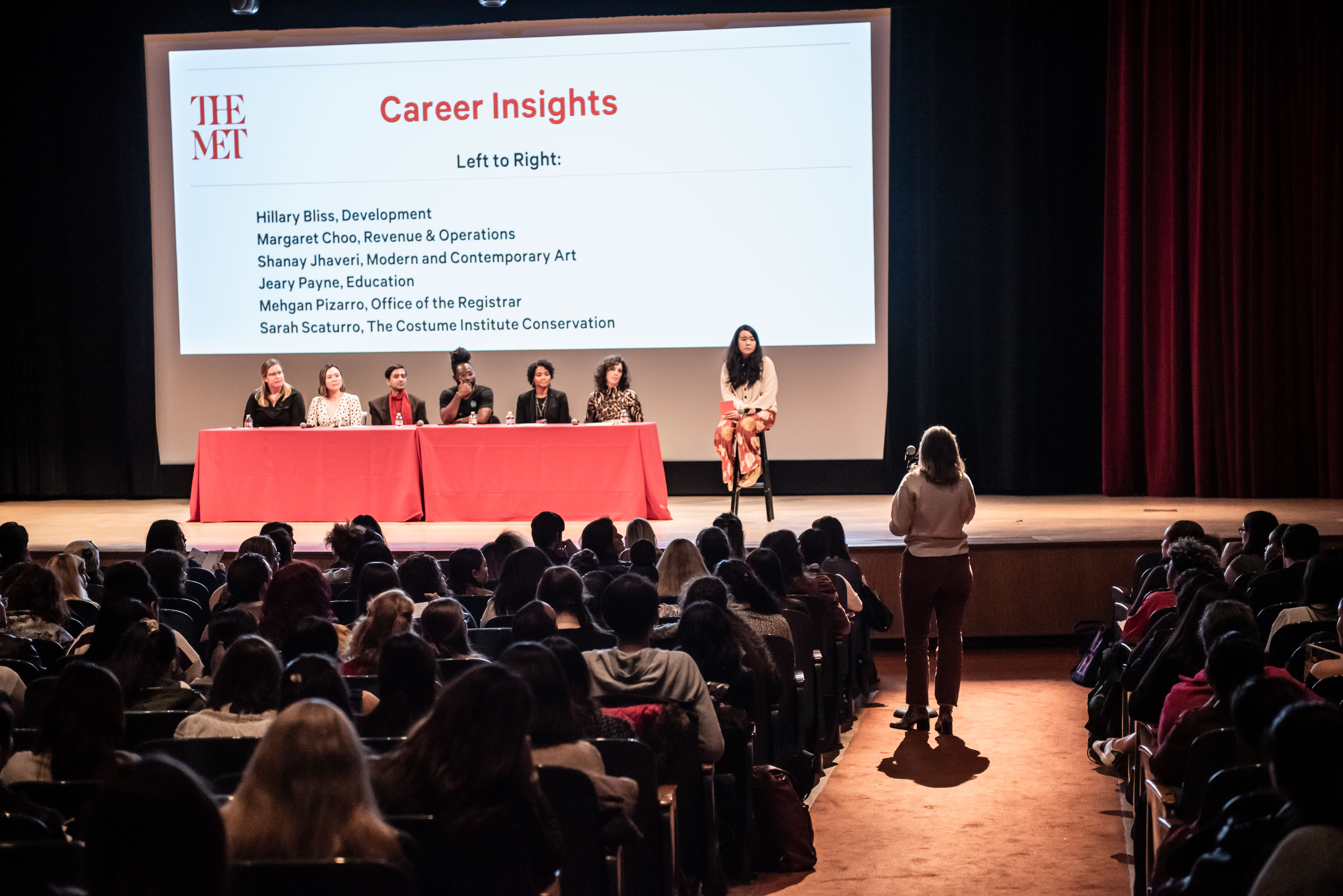 A panel of seven individuals on a stage in front of a presentation entitled "Career Insights"